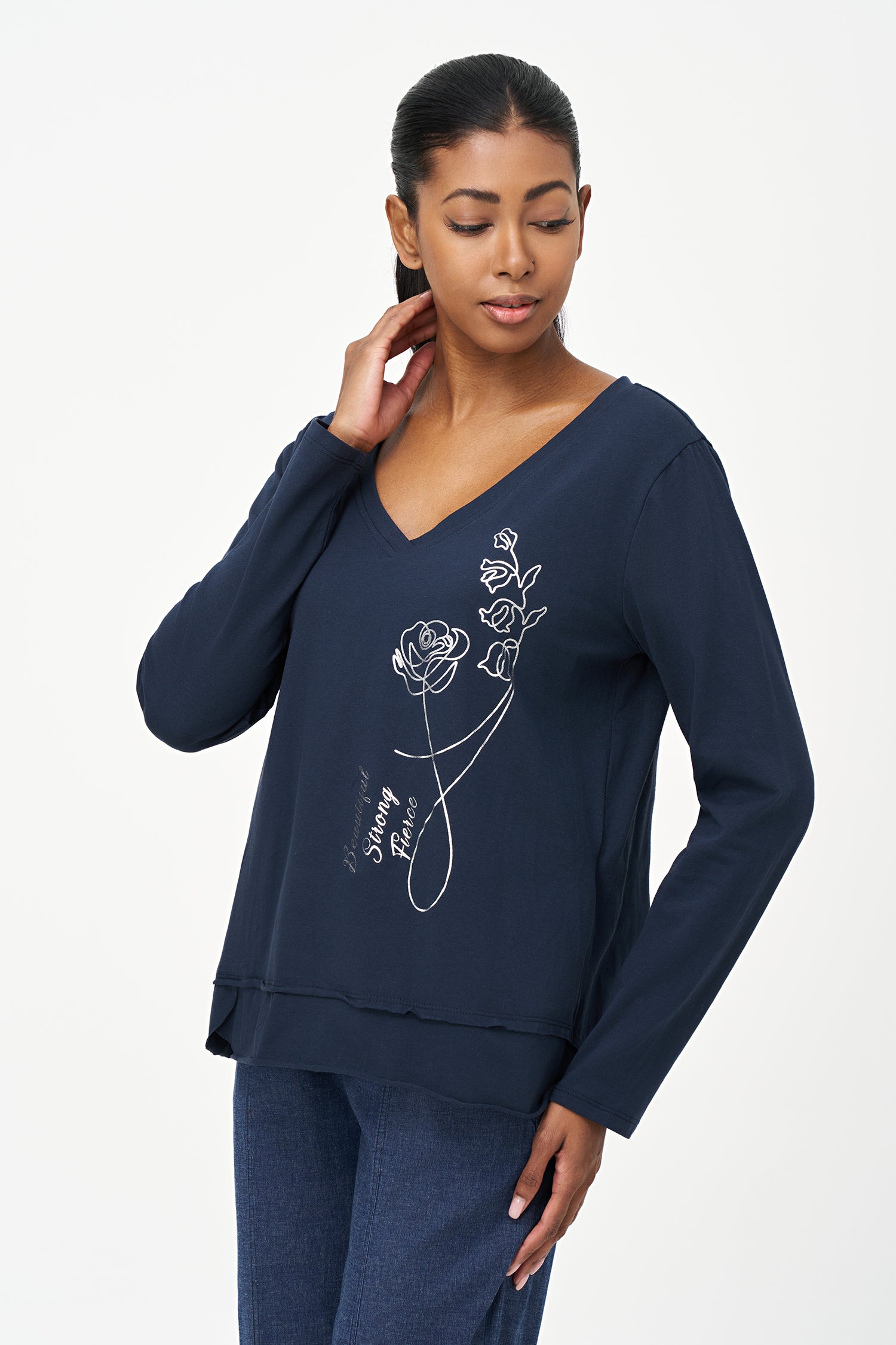 Blue V-neck long-sleeve top with white embroidered floral design and cursive script reading 'Beautiful, Bonjour, Fleur' on the front.