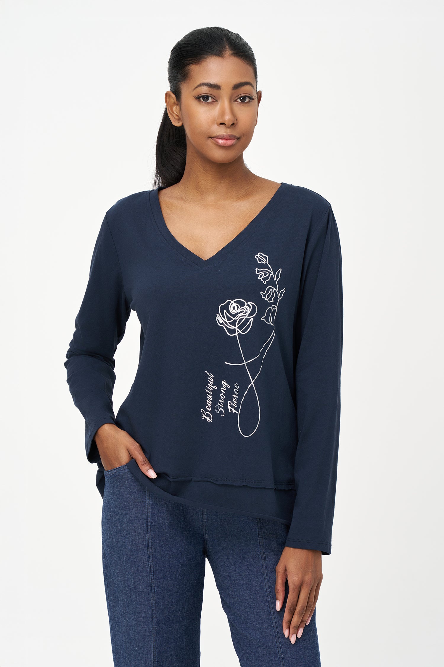 Blue V-neck long-sleeve top with white embroidered floral design and cursive script reading 'Beautiful, Bonjour, Fleur' on the front.