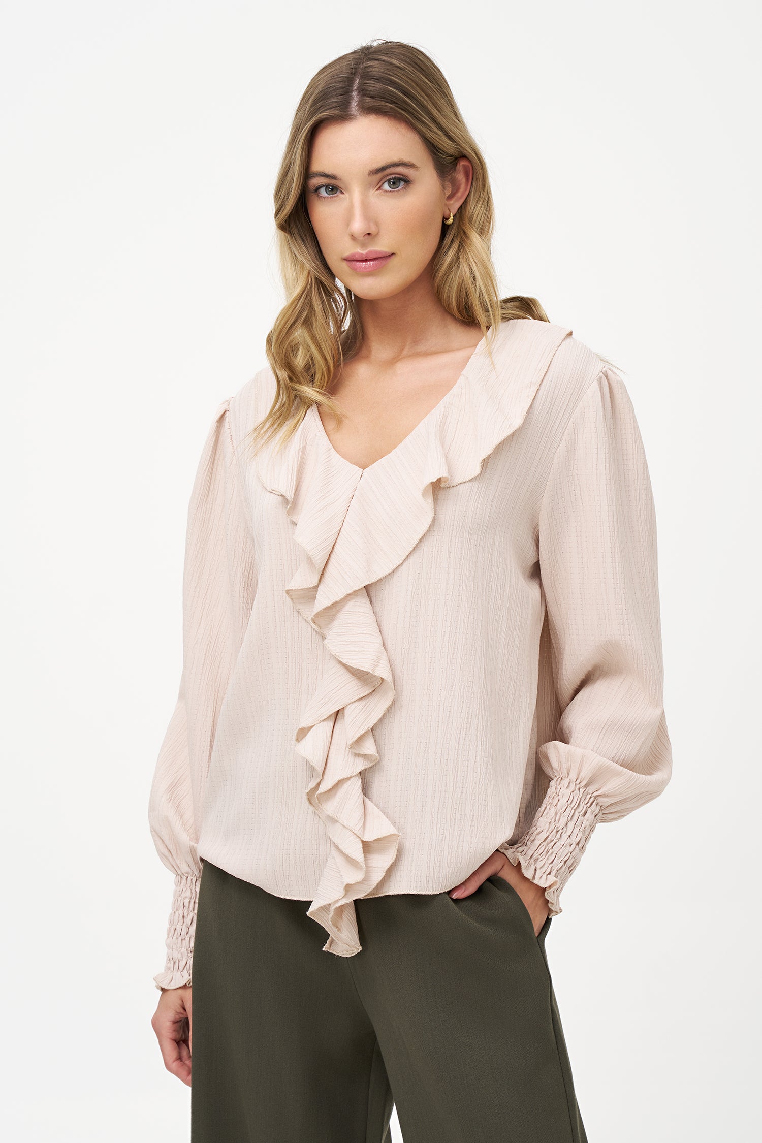 Elegant white long-sleeve blouse with vertical pleats, dramatic front ruffle, and smocked cuffs.