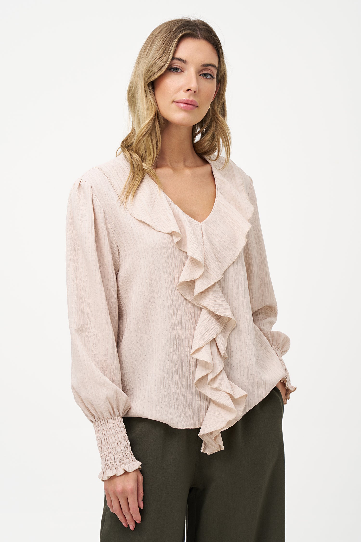 Elegant white long-sleeve blouse with vertical pleats, dramatic front ruffle, and smocked cuffs.