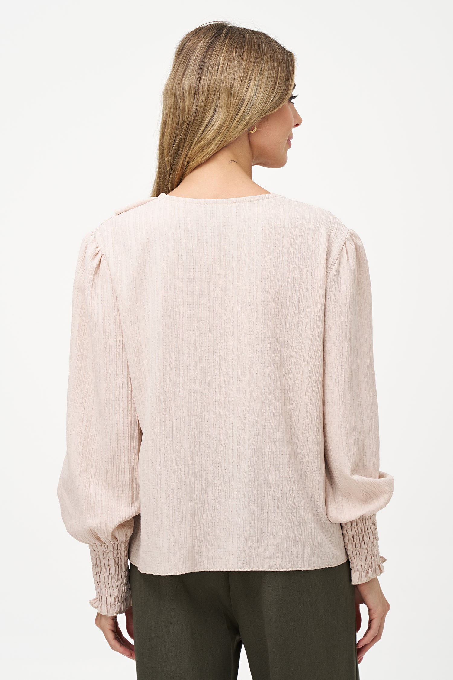 Elegant white long-sleeve blouse with vertical pleats, dramatic front ruffle, and smocked cuffs.
