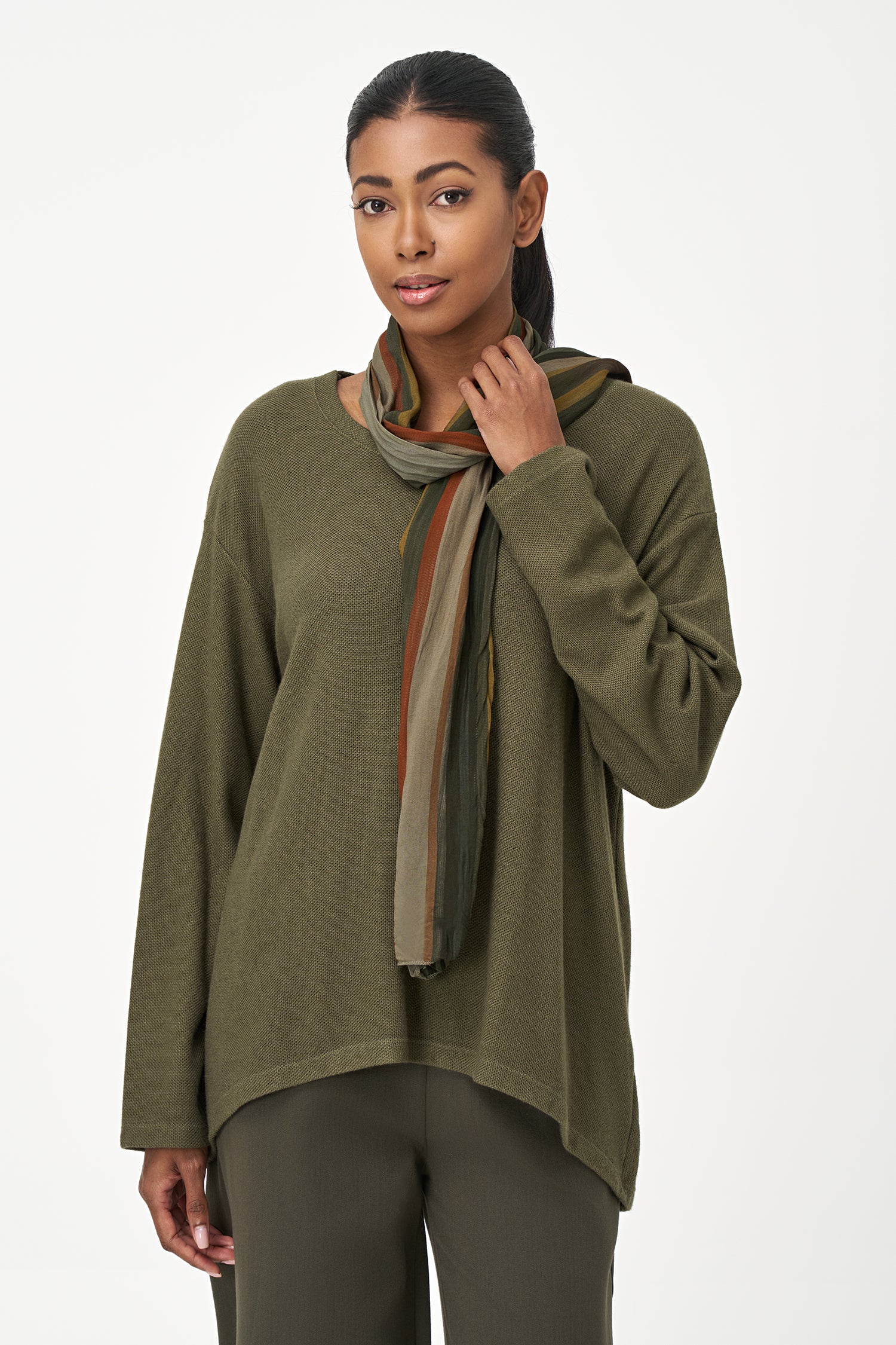 Olive green long sleeve top with a rounded hem and attached multicolor striped scarf, perfect for fall layering.