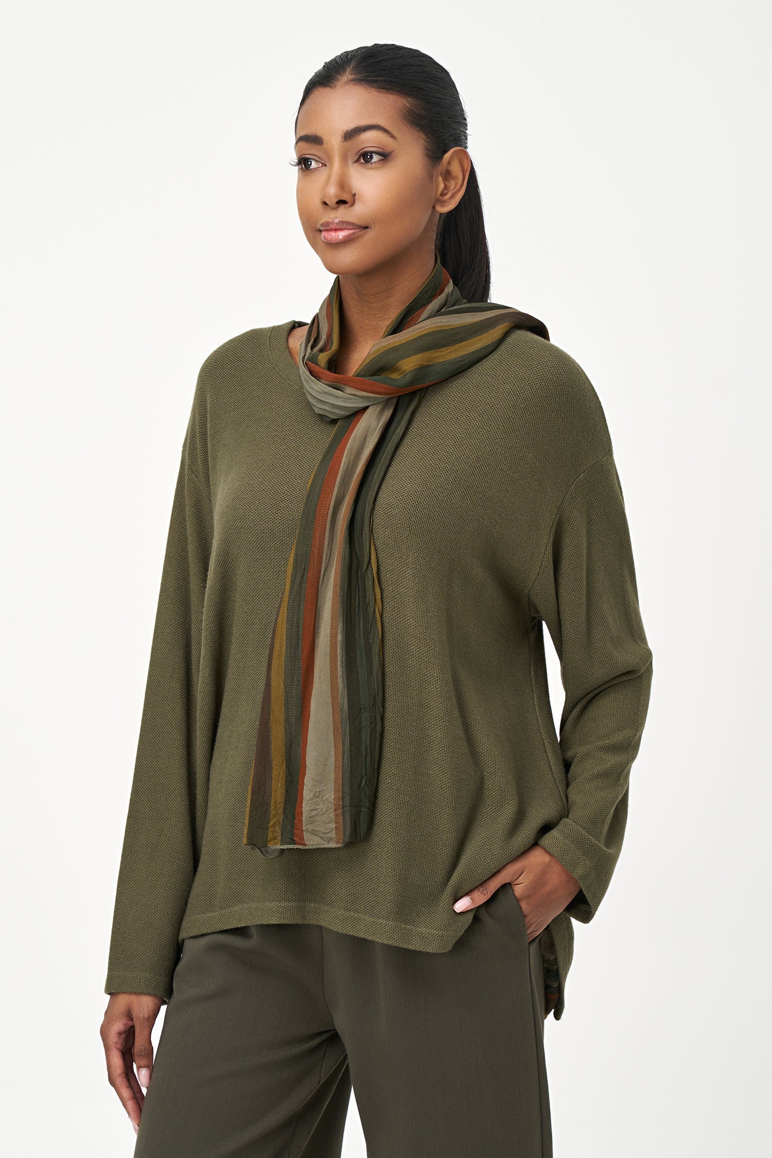 Olive green long sleeve top with a rounded hem and attached multicolor striped scarf, perfect for fall layering.