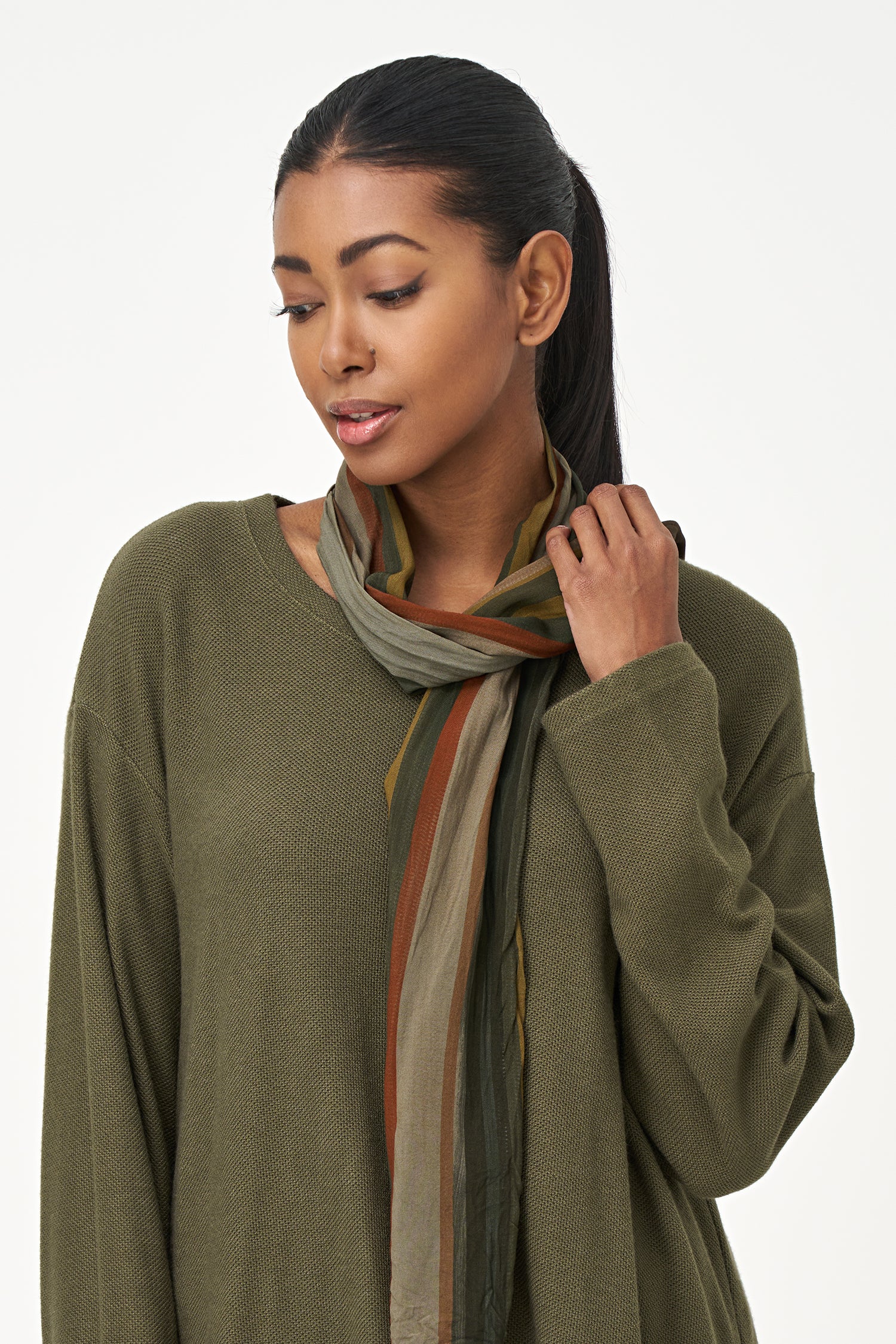 Olive green long sleeve top with a rounded hem and attached multicolor striped scarf, perfect for fall layering.