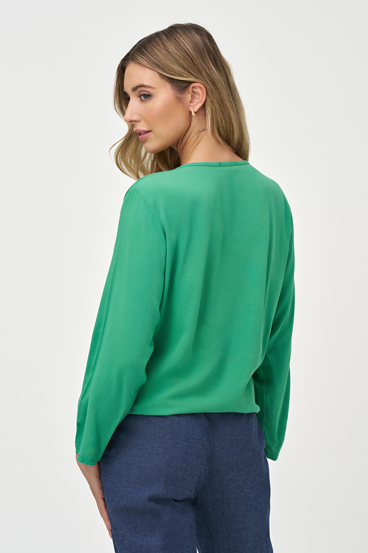 Green V-neck long sleeve top with front tie detail and relaxed silhouette.