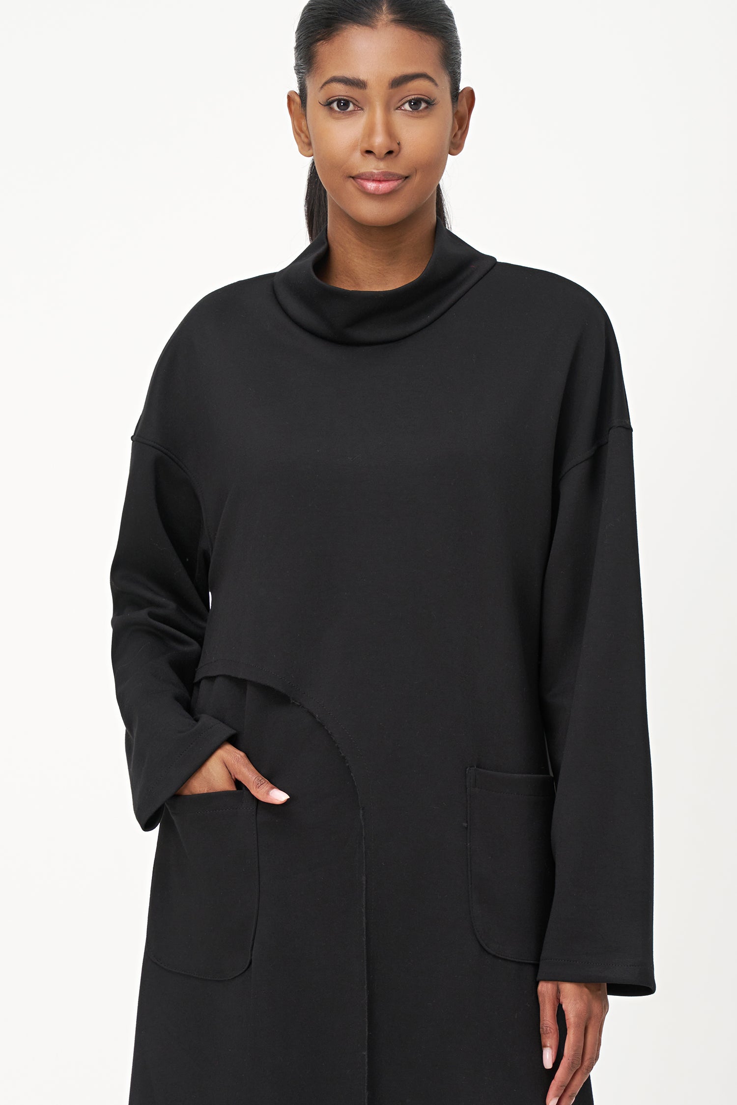 Black long sleeve mock neck dress with asymmetrical front seam and rounded side patch pocket