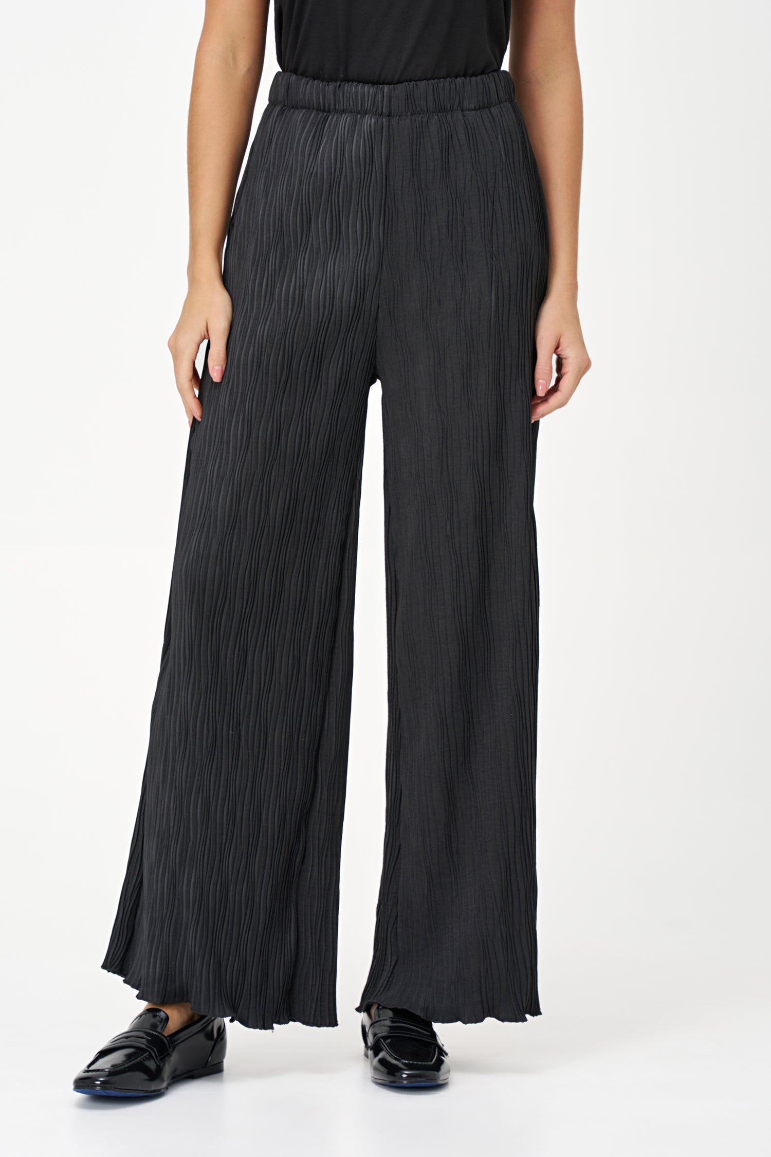 Black wide-leg crinkle pants with an elastic waistband and subtle wave texture, featuring a soft drape and flowy silhouette.