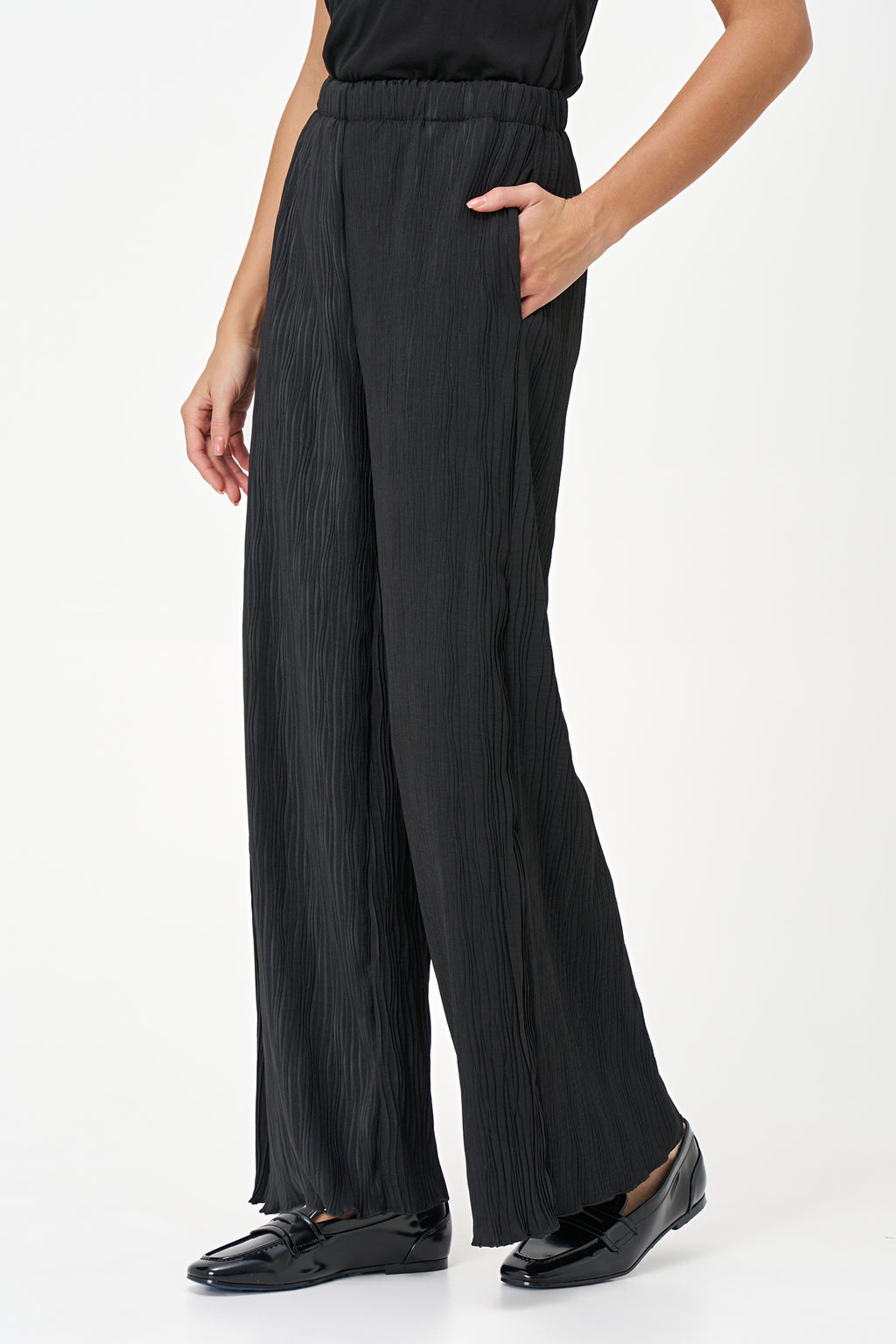 Black wide-leg crinkle pants with an elastic waistband and subtle wave texture, featuring a soft drape and flowy silhouette.