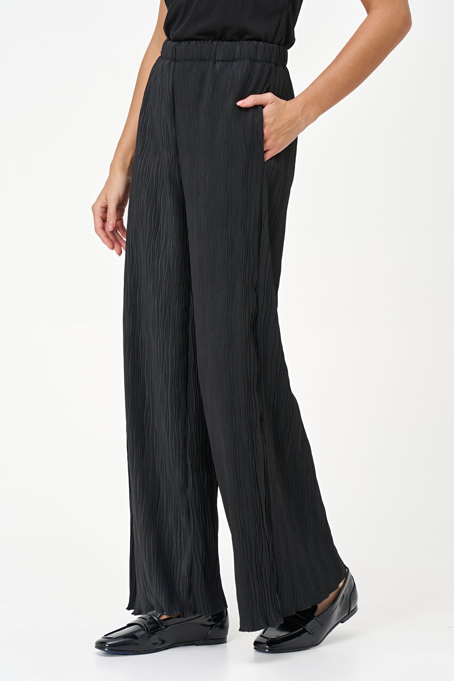 Black wide-leg crinkle pants with an elastic waistband and subtle wave texture, featuring a soft drape and flowy silhouette.
