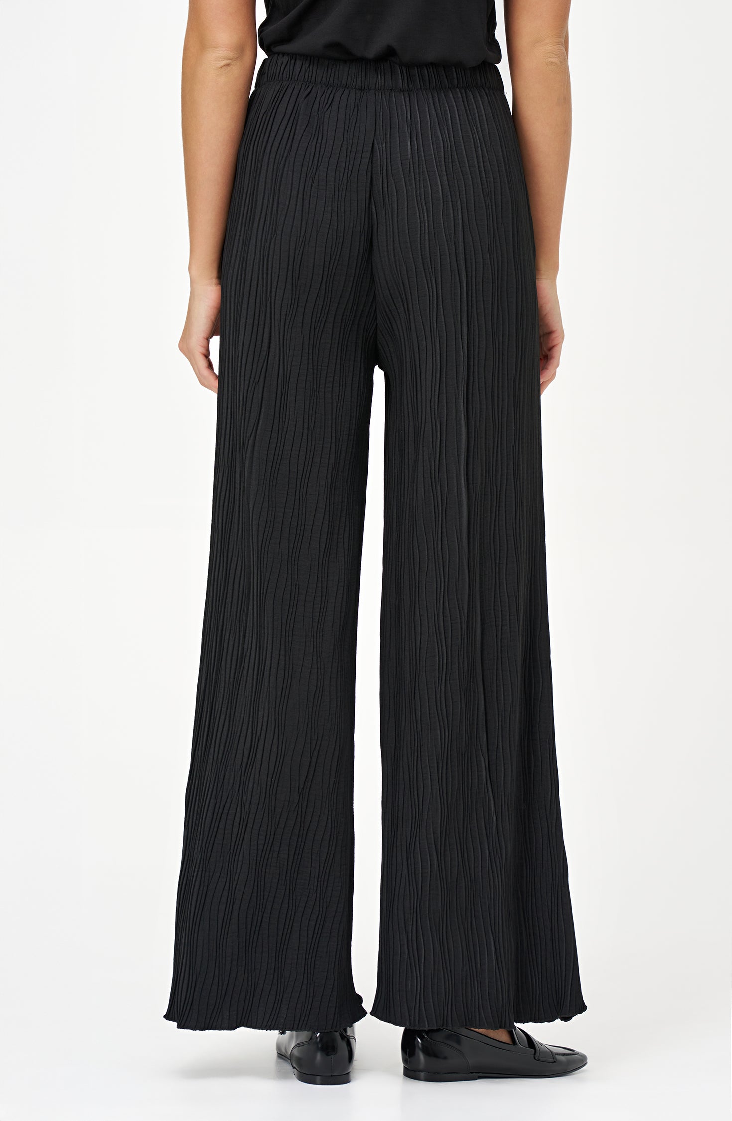 Black wide-leg crinkle pants with an elastic waistband and subtle wave texture, featuring a soft drape and flowy silhouette.