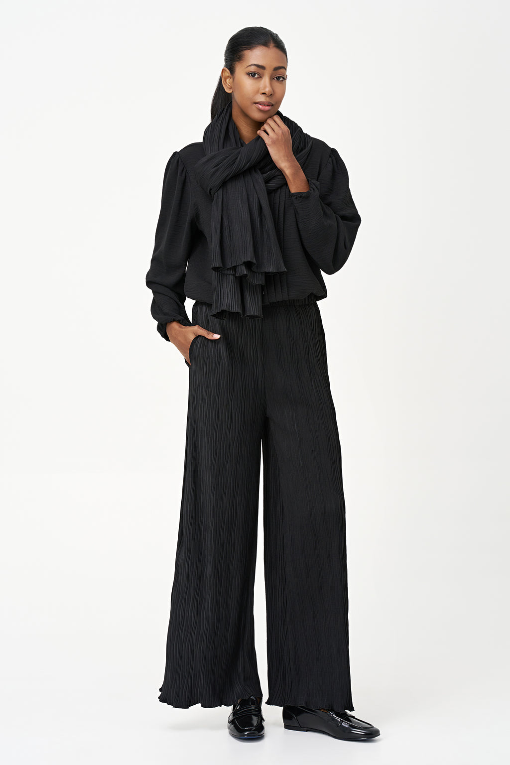 Black wide-leg crinkle pants with an elastic waistband and subtle wave texture, featuring a soft drape and flowy silhouette.