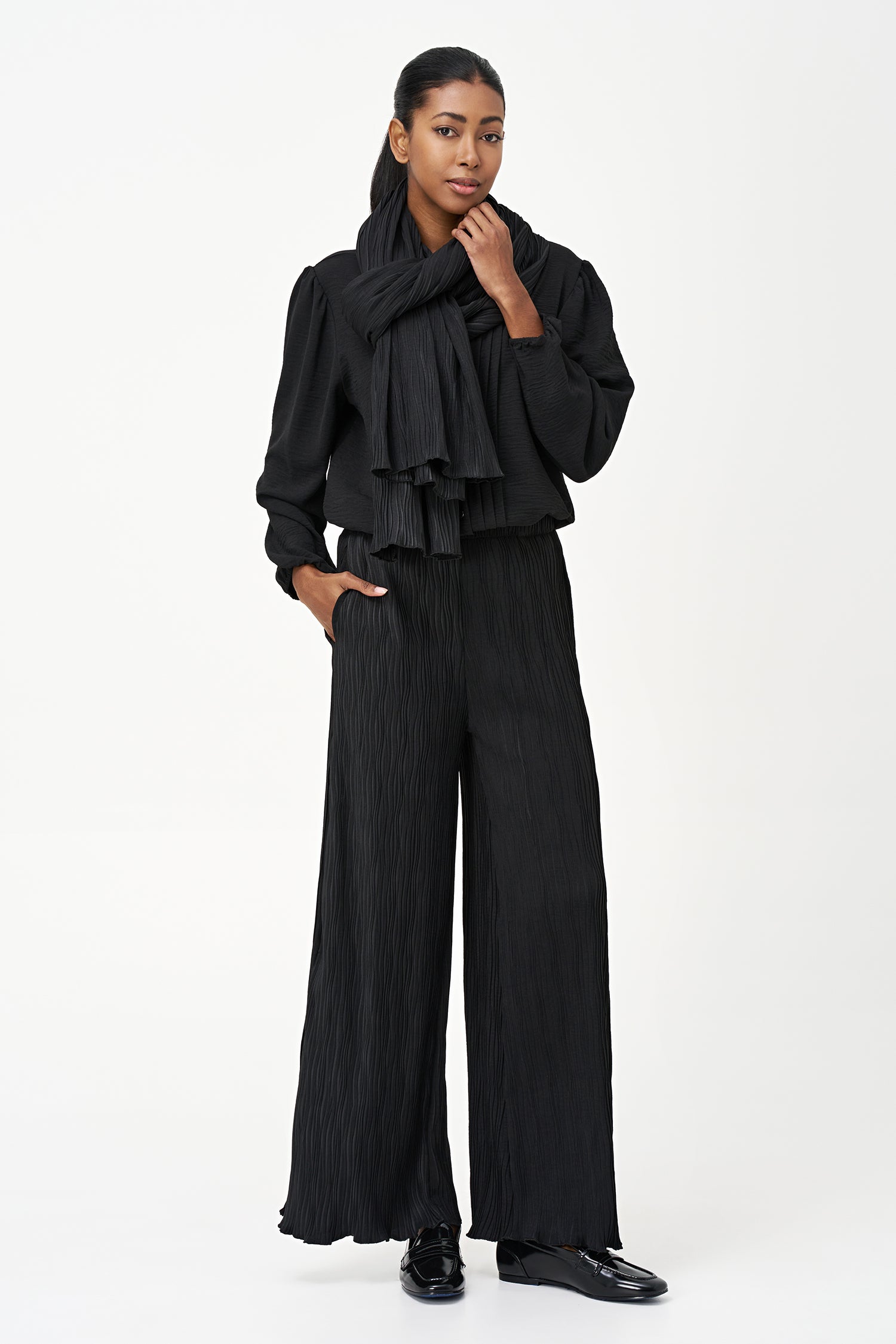 Black wide-leg crinkle pants with an elastic waistband and subtle wave texture, featuring a soft drape and flowy silhouette.