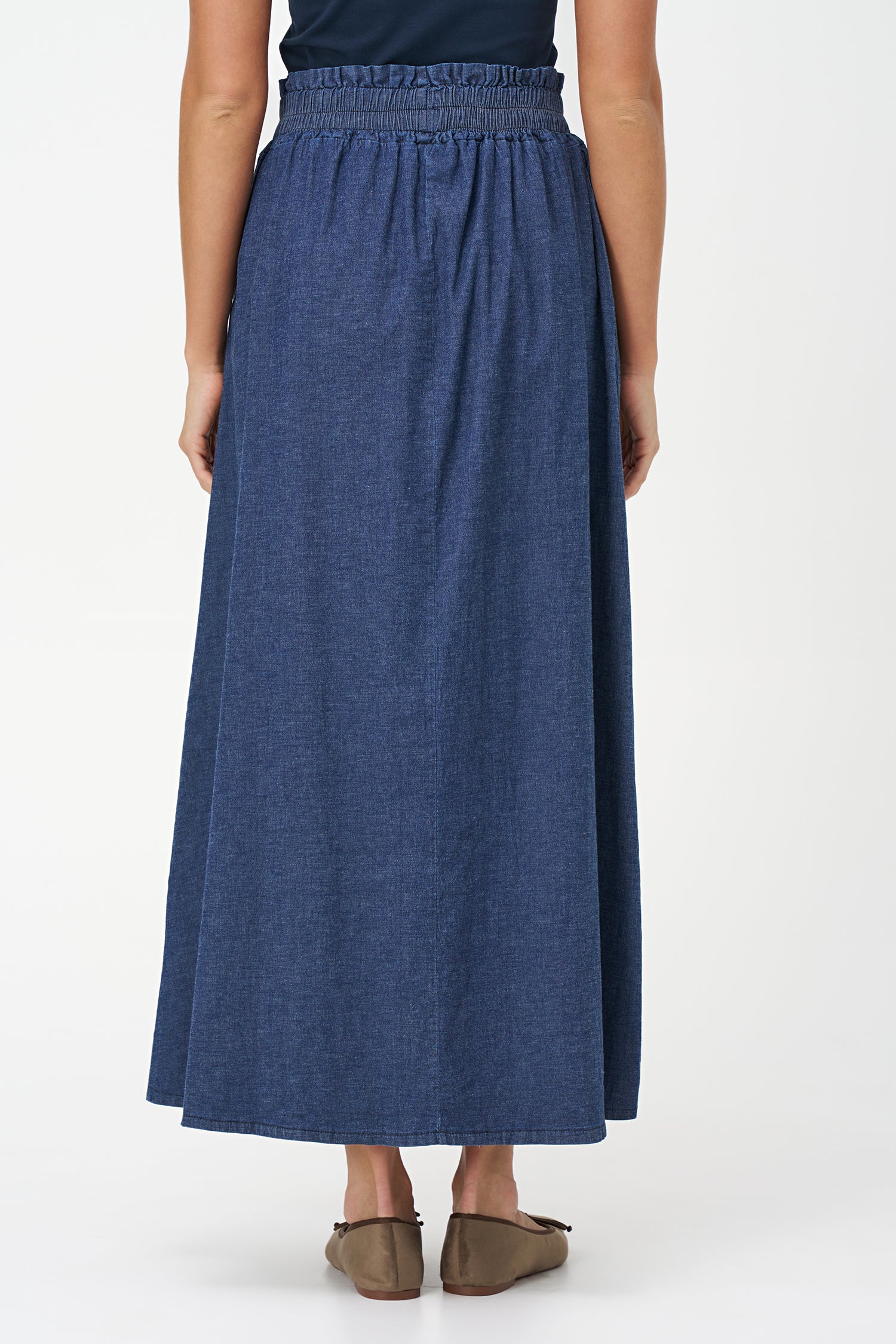 Navy denim maxi skirt in 100% cotton with a gathered elastic waistband and a soft A-line silhouette for casual elegance.