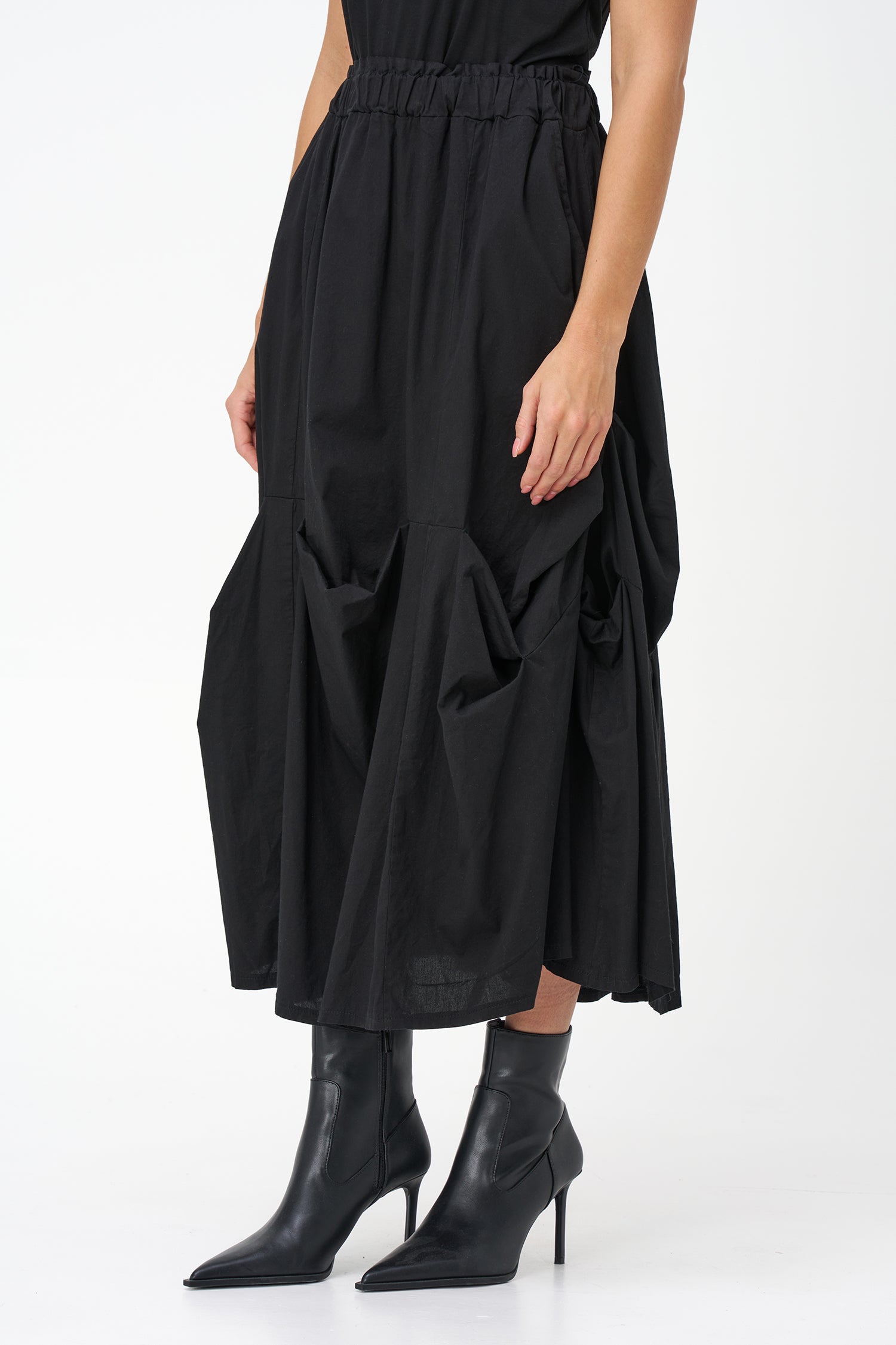Black cotton midi skirt with unique gathered pocket detailing and elastic waistband, combining comfort with avant-garde flair.