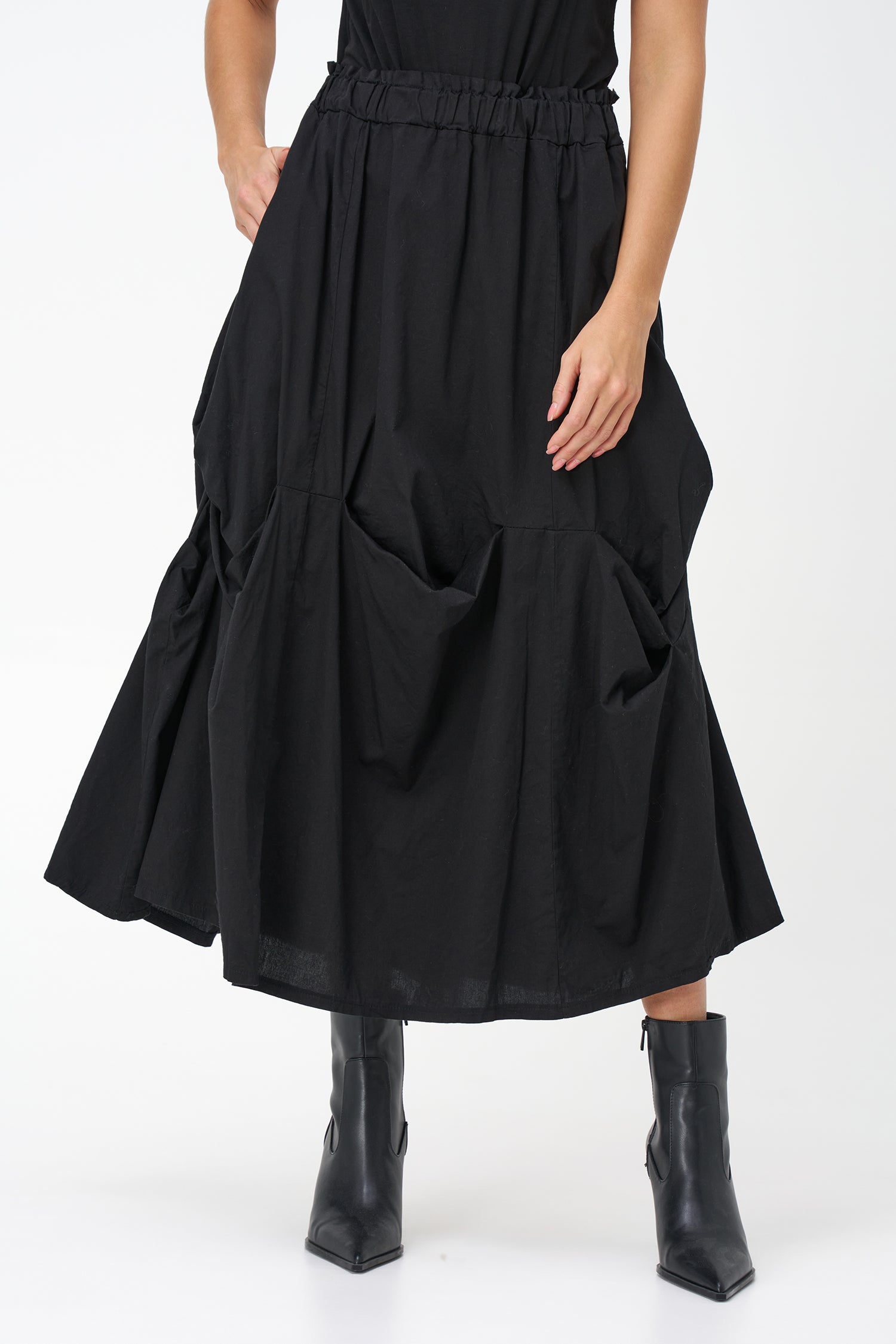 Black cotton midi skirt with unique gathered pocket detailing and elastic waistband, combining comfort with avant-garde flair.