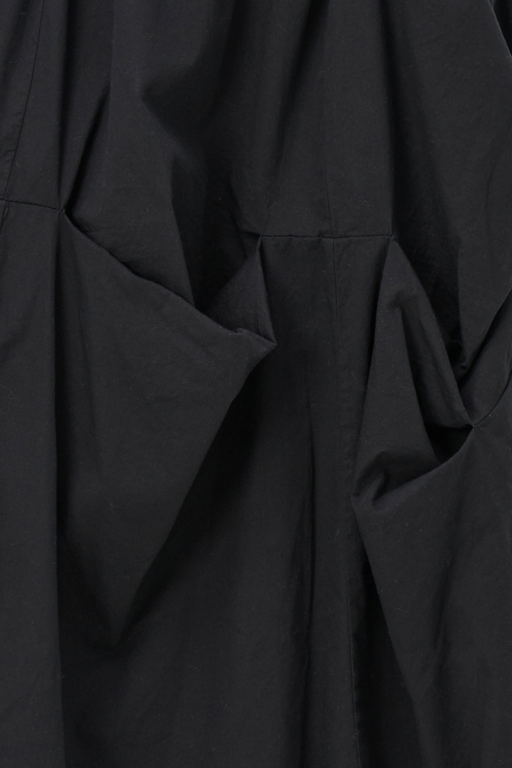 Black cotton midi skirt with unique gathered pocket detailing and elastic waistband, combining comfort with avant-garde flair.
