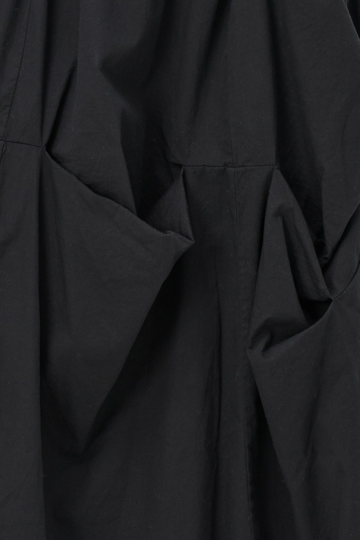 Black cotton midi skirt with unique gathered pocket detailing and elastic waistband, combining comfort with avant-garde flair.