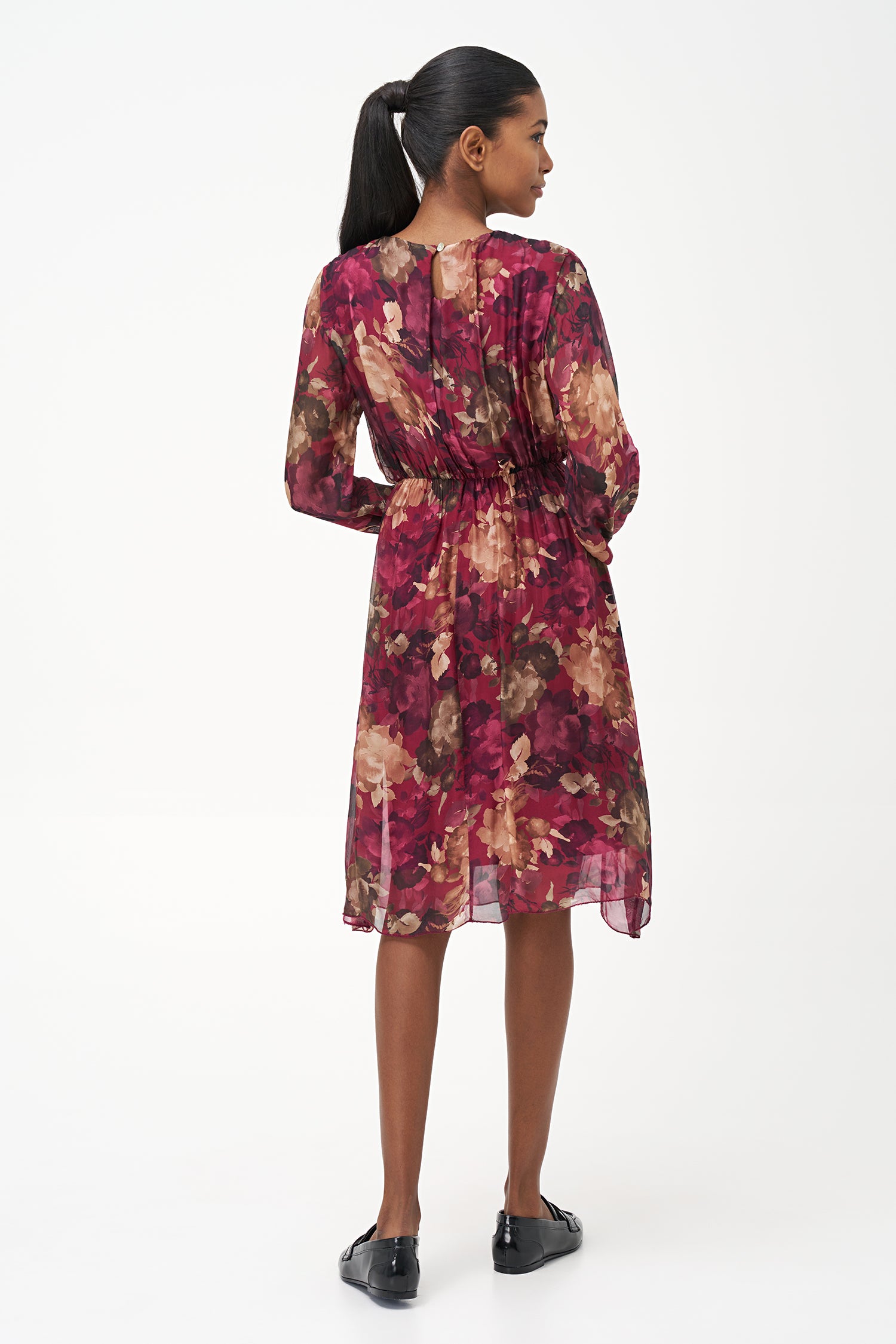 Sheer long-sleeve floral dress in warm earthy tones with gathered neckline and back keyhole detail.