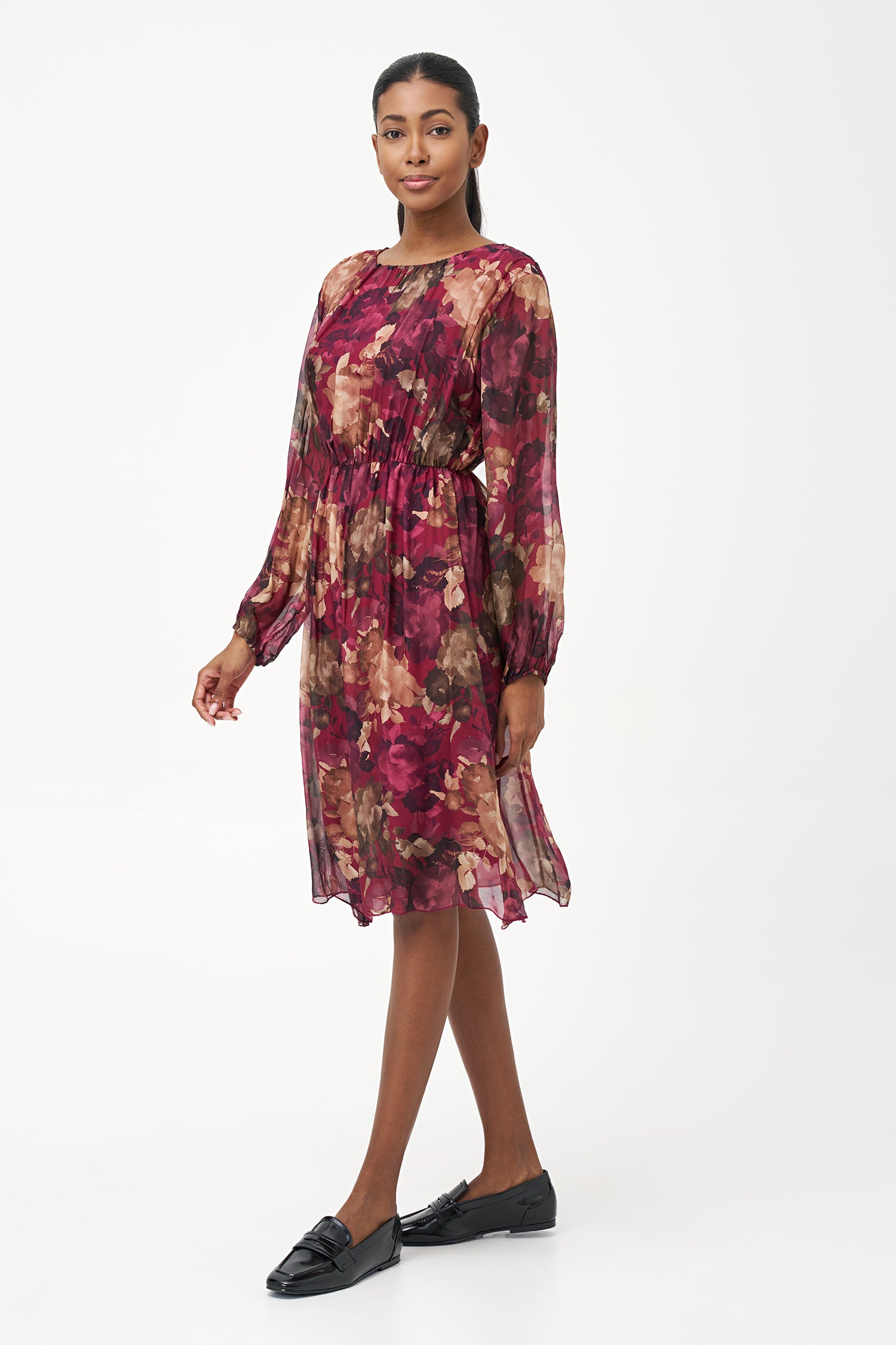 Sheer long-sleeve floral dress in warm earthy tones with gathered neckline and back keyhole detail.
