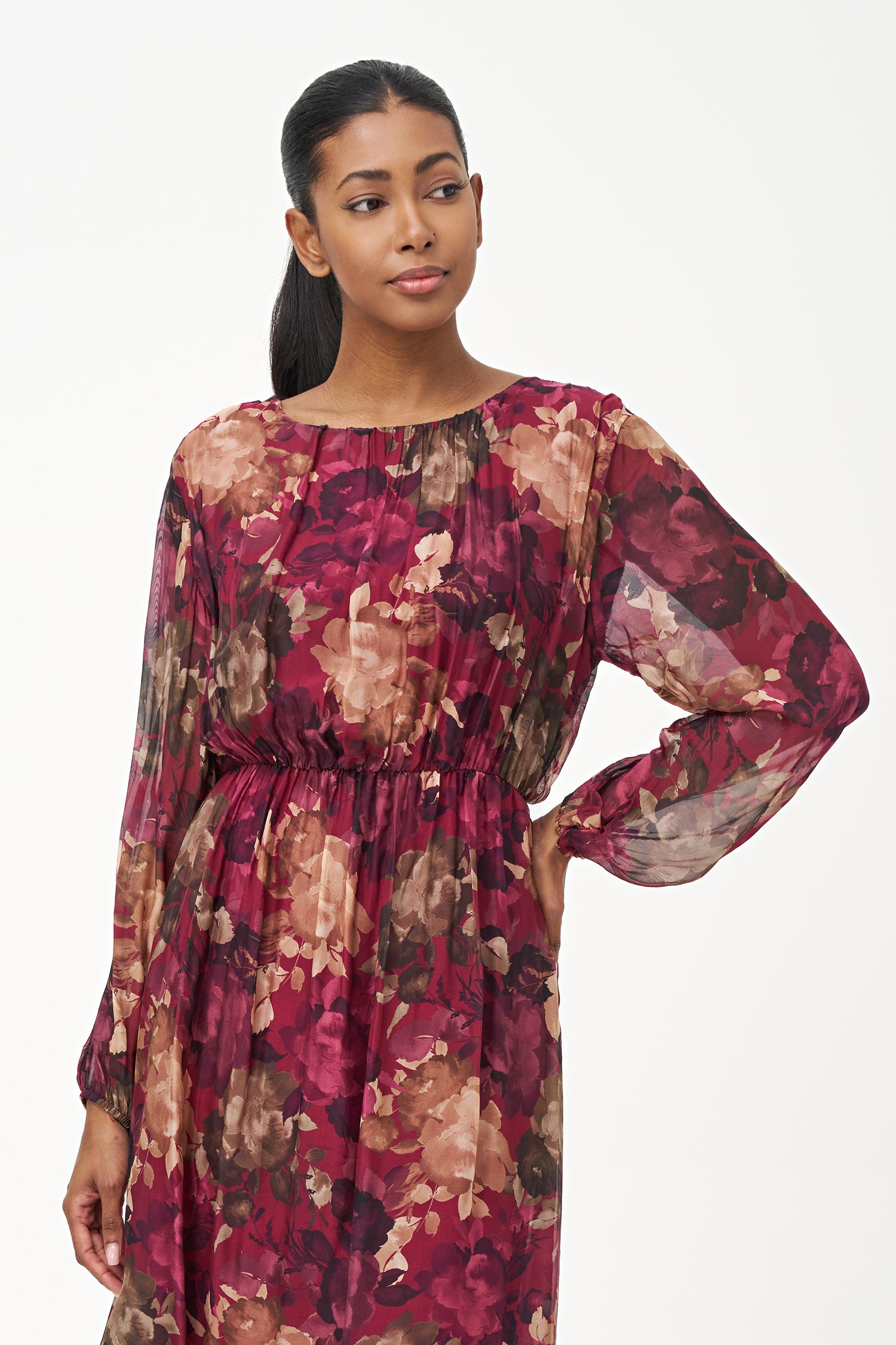 Sheer long-sleeve floral dress in warm earthy tones with gathered neckline and back keyhole detail.