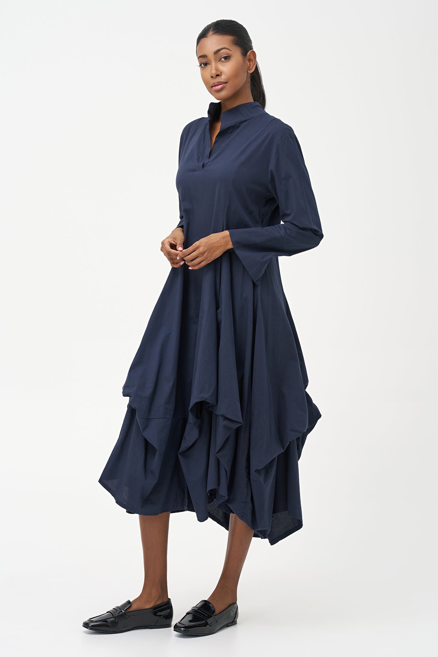 Blue high-neck cotton dress with long sleeves and dramatic draped asymmetric hem.