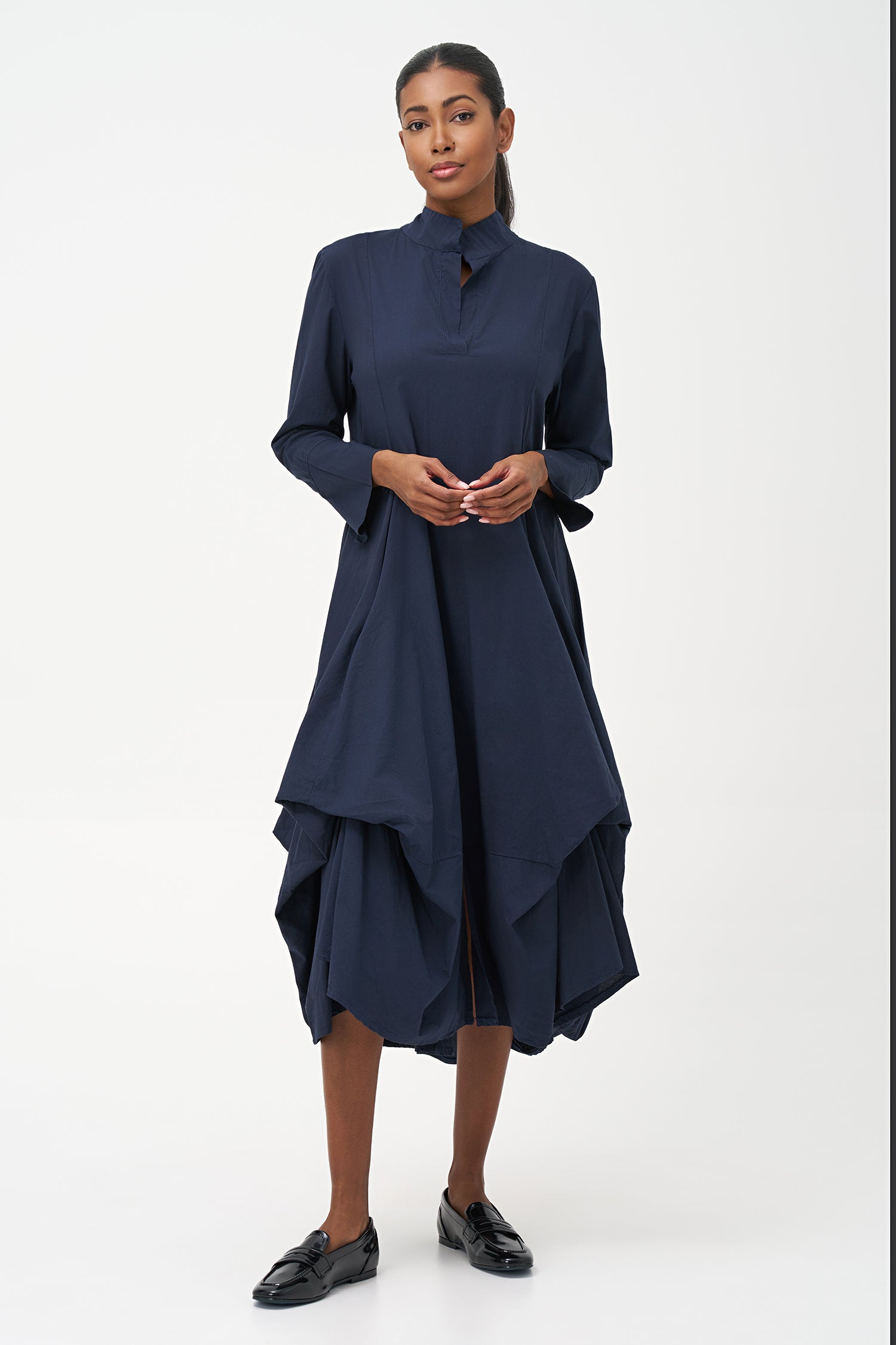 Blue high-neck cotton dress with long sleeves and dramatic draped asymmetric hem.