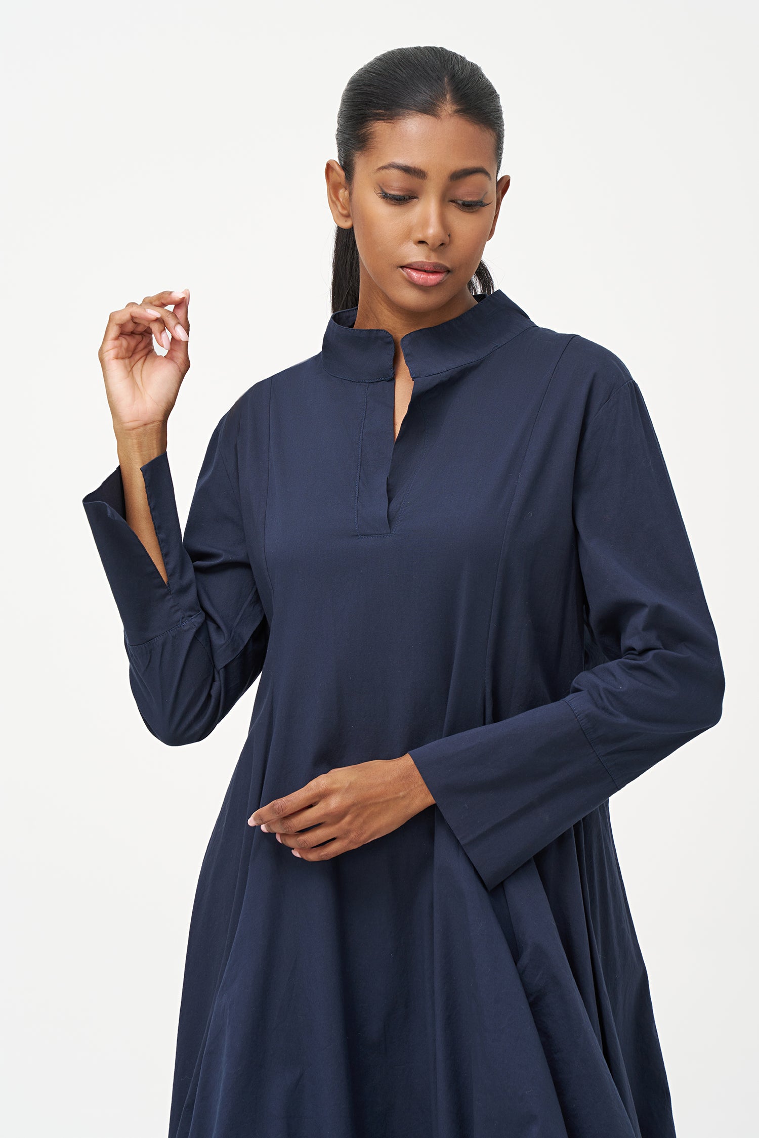Blue high-neck cotton dress with long sleeves and dramatic draped asymmetric hem.