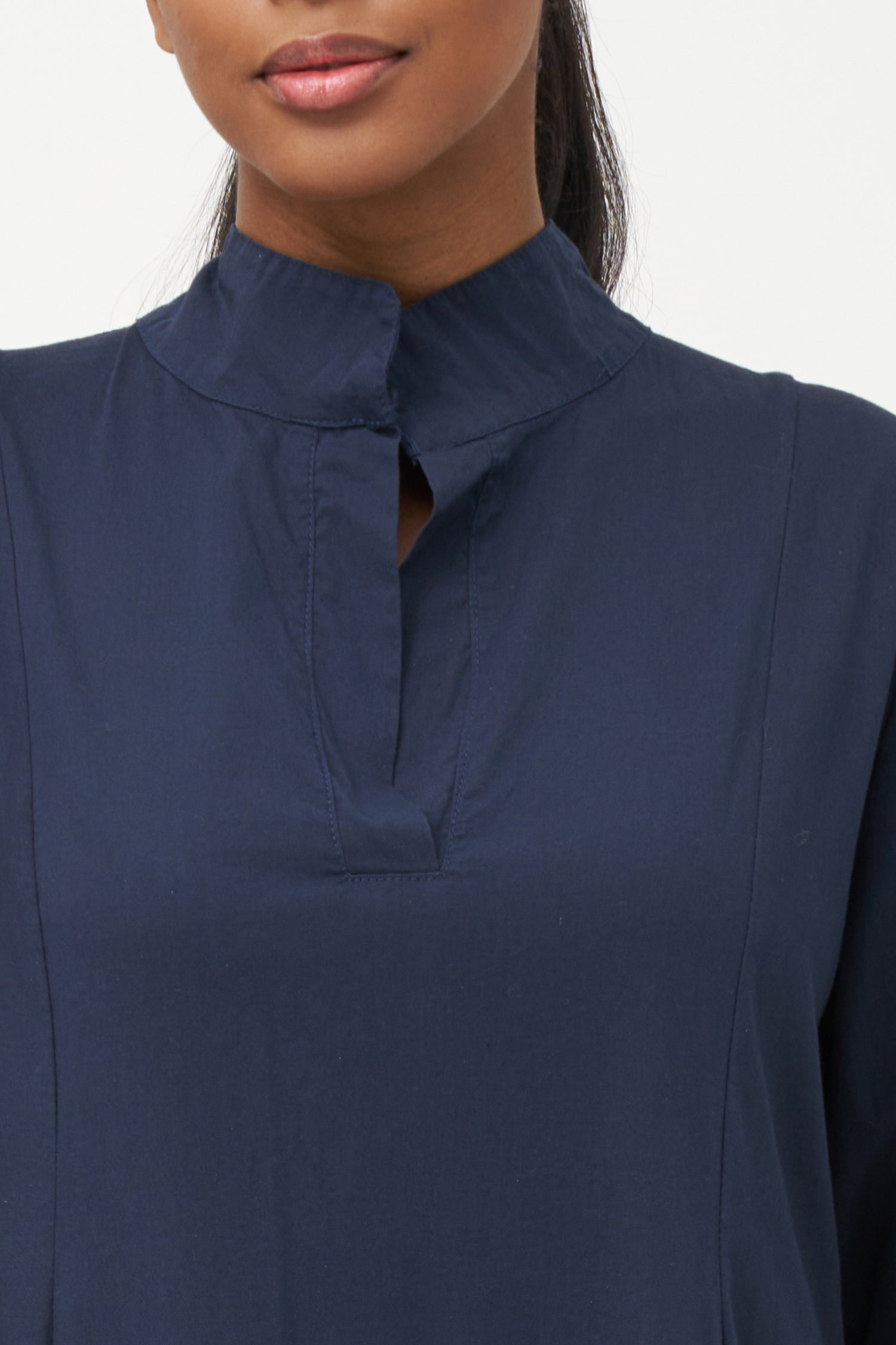 Blue high-neck cotton dress with long sleeves and dramatic draped asymmetric hem.