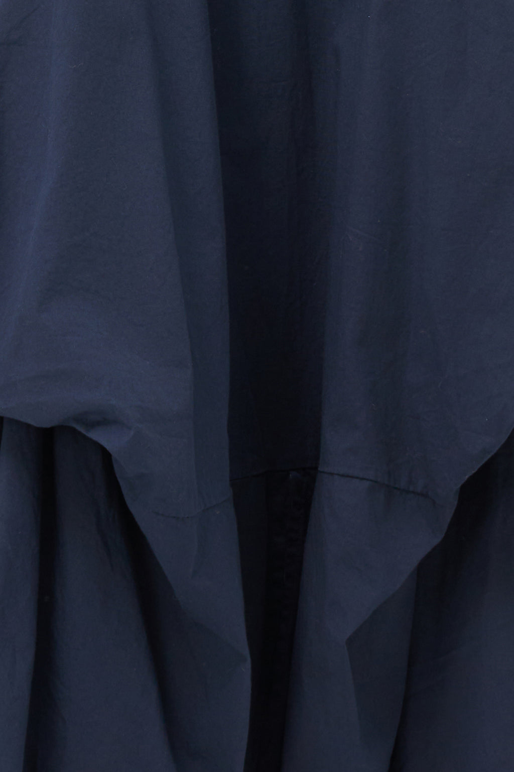 Blue high-neck cotton dress with long sleeves and dramatic draped asymmetric hem.