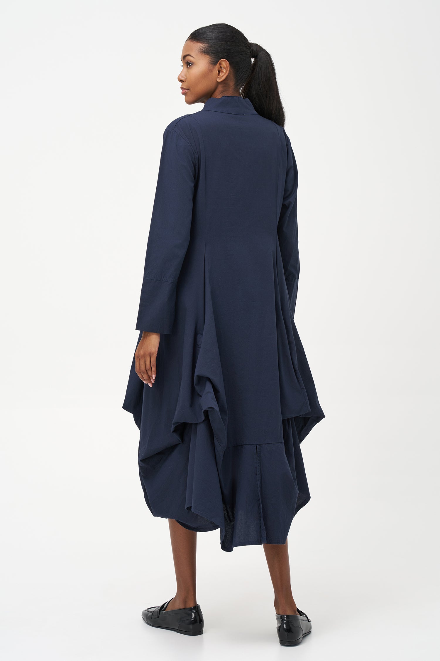Blue high-neck cotton dress with long sleeves and dramatic draped asymmetric hem.