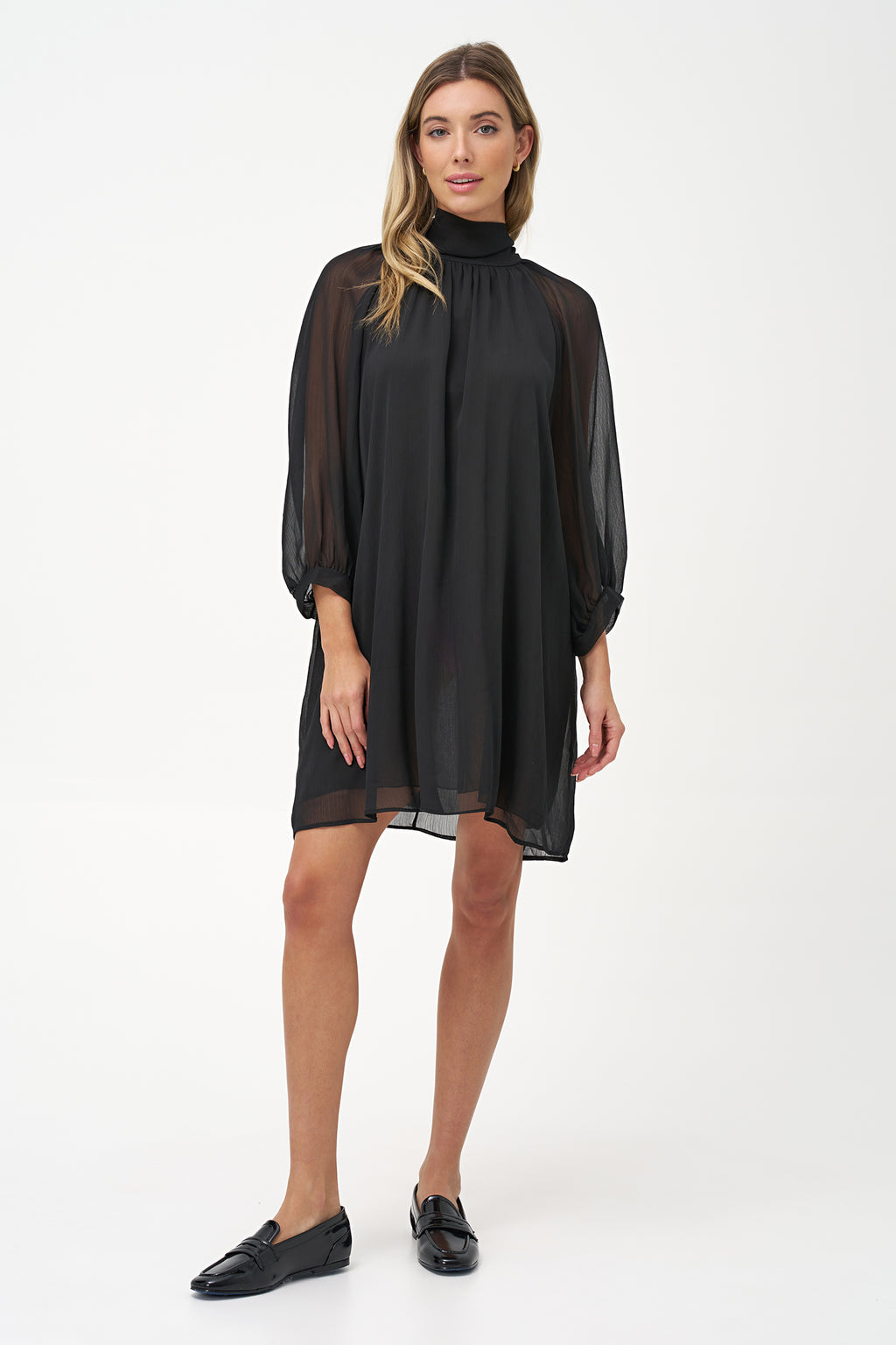 Sheer long-sleeve black dress with high neck and oversized bow detail.