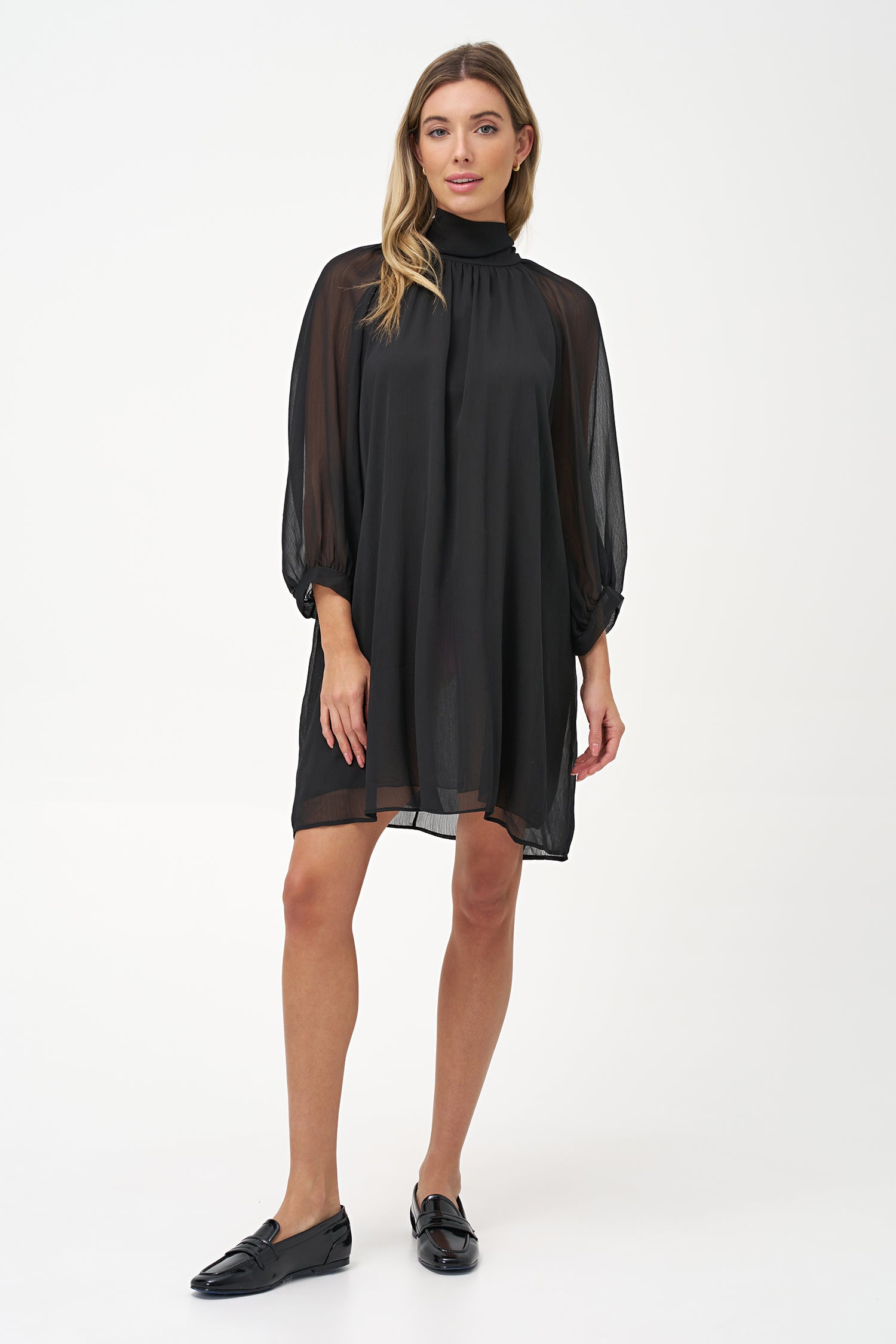 Sheer long-sleeve black dress with high neck and oversized bow detail.