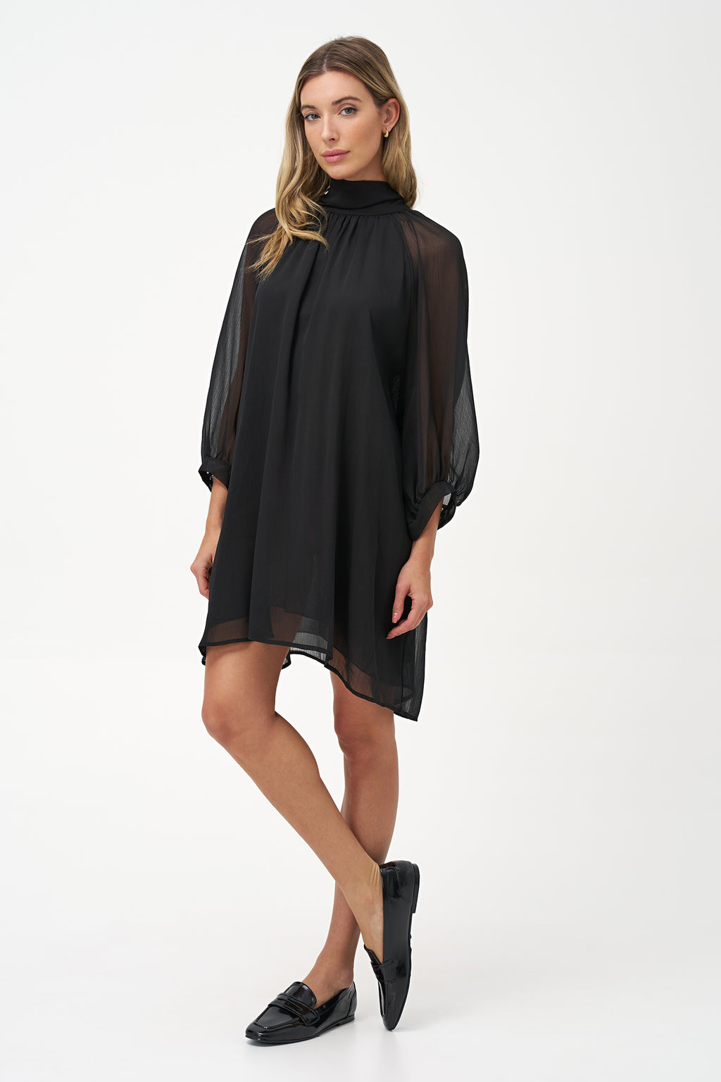 Sheer long-sleeve black dress with high neck and oversized bow detail.