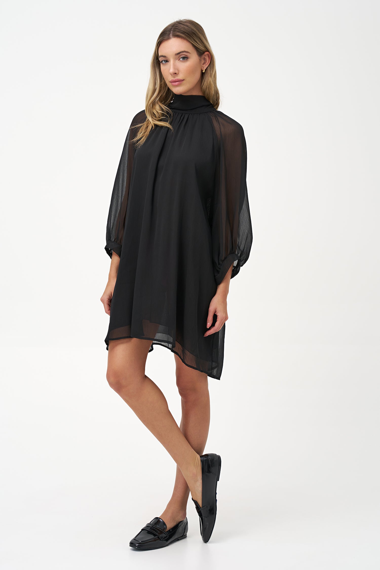 Sheer long-sleeve black dress with high neck and oversized bow detail.
