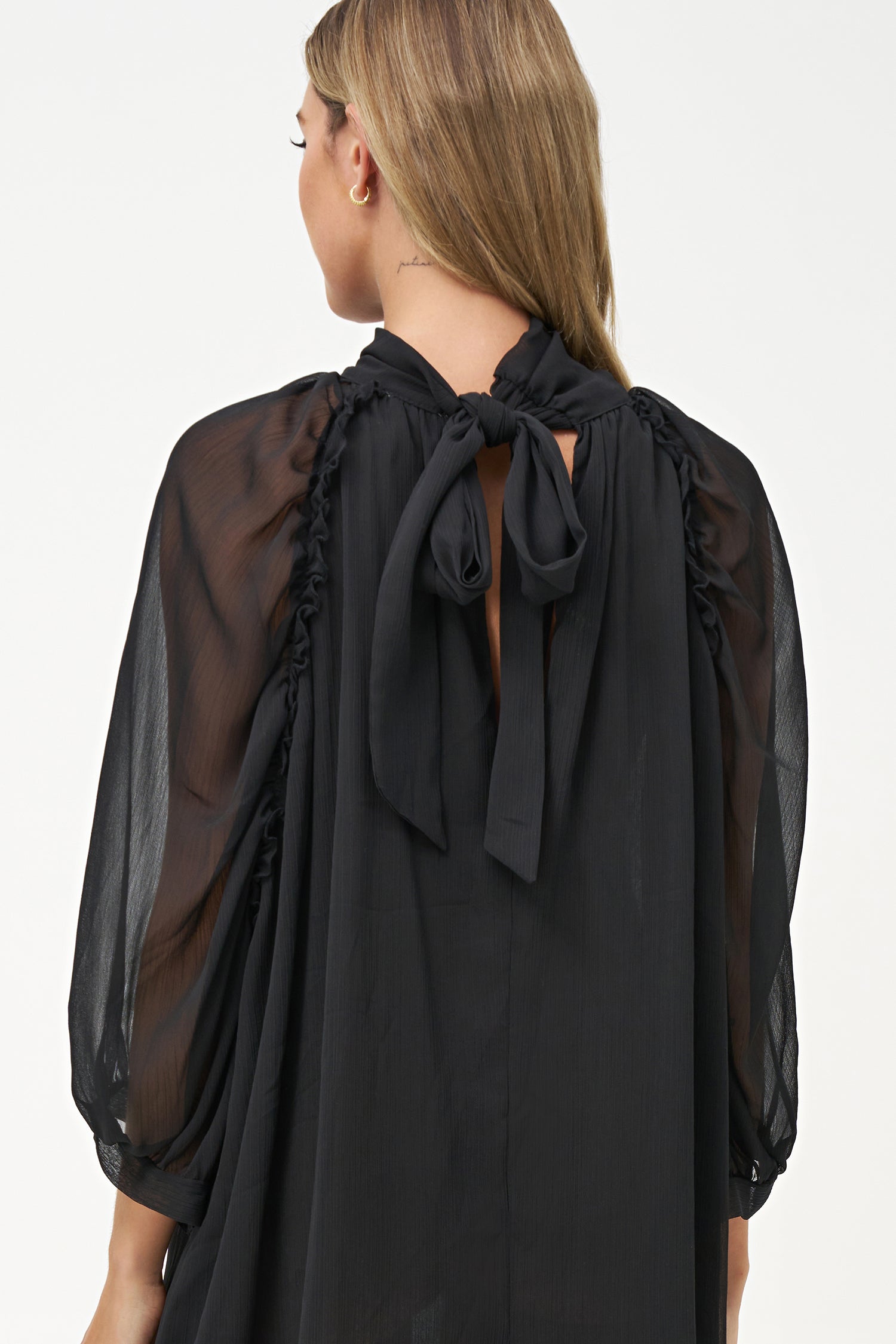 Sheer long-sleeve black dress with high neck and oversized bow detail.