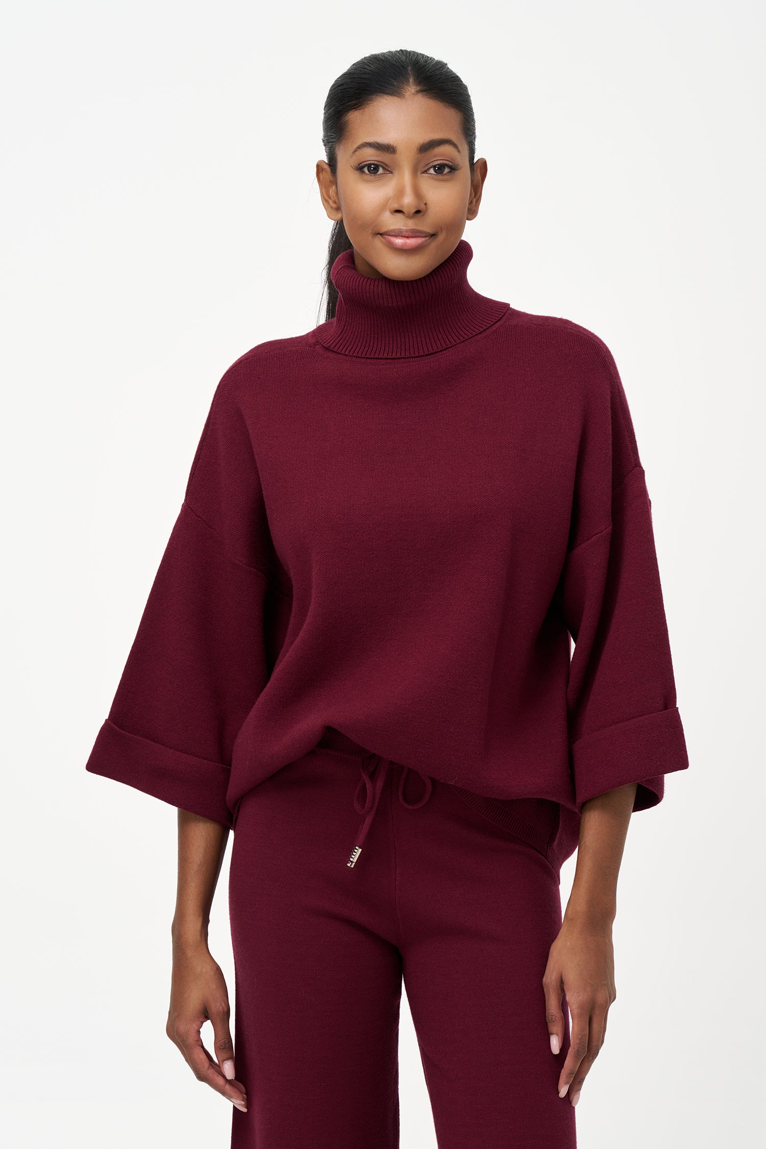 red turtleneck top with wide 3/4 sleeves, folded cuffs, and a structured silhouette for casual or polished styling.