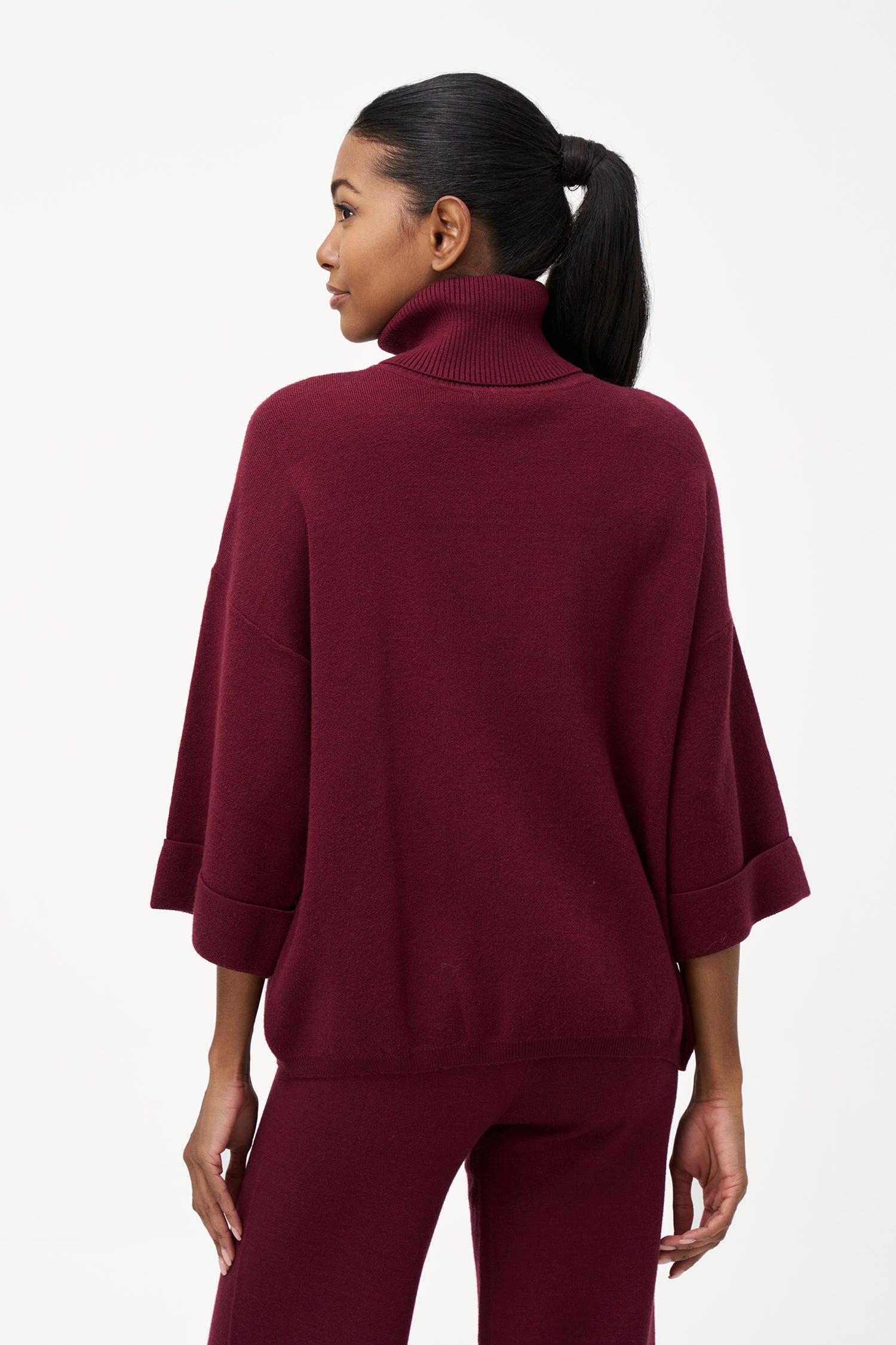red turtleneck top with wide 3/4 sleeves, folded cuffs, and a structured silhouette for casual or polished styling.